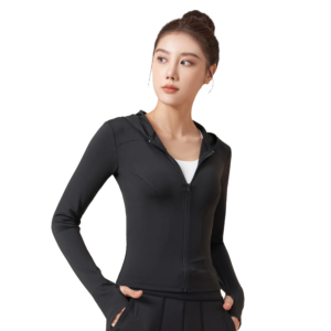 A woman wears a black zip-up hooded jacket with a V-neck collar, her hands casually resting in the pockets.