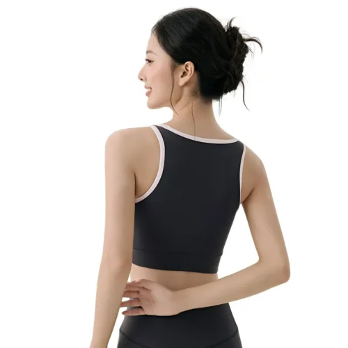 a sports bra. The model has dark, slightly tousled long hair falling over her shoulders. The bra is in a slate blue or dusty blue color with distinct off-white contrast piping that outlines the U-shaped neckline and straps.