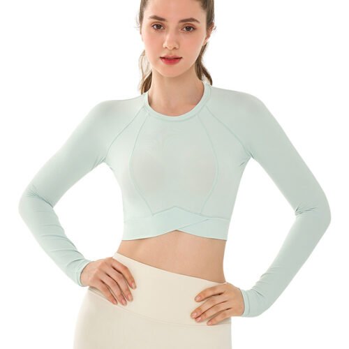 Alternative Text A woman models a mint green long-sleeve crop top. The top features a round neck, soft stretchy fabric, and a cropped, waist-skimming fit. She stands with hands on hips, paired with white bottoms. The clean white background highlights the fresh, minimalist style of the outfit. Title for Google Search Mint Green Long Sleeve Crop Top for Women - Round Neck Soft Stretch Shirt, Cropped Fitness Top with White Bottoms