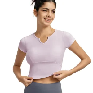 a light pink short-sleeve V-neck top. The fitted top features a subtle curved notch detail at the neckline, emphasizing the stretchy fabric.