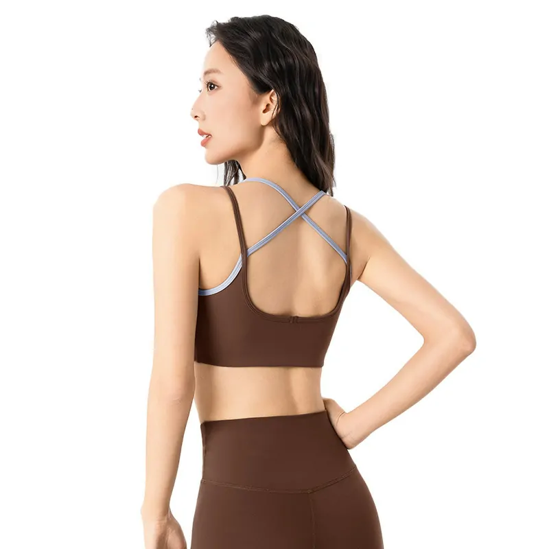 showcasing a brown sports bra with a cross-back strap design. The minimalist X-shaped straps and solid color are highlighted against a clean