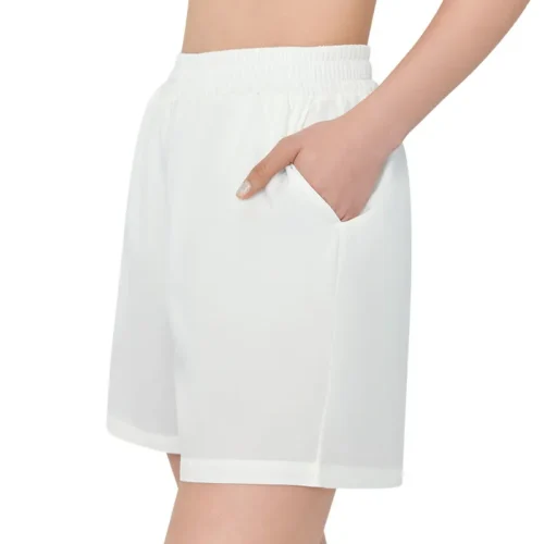 A woman's hand sliding into the pocket of a pair of white mid-thigh casual shorts, highlighting the pocket detail and soft drape of the fabric