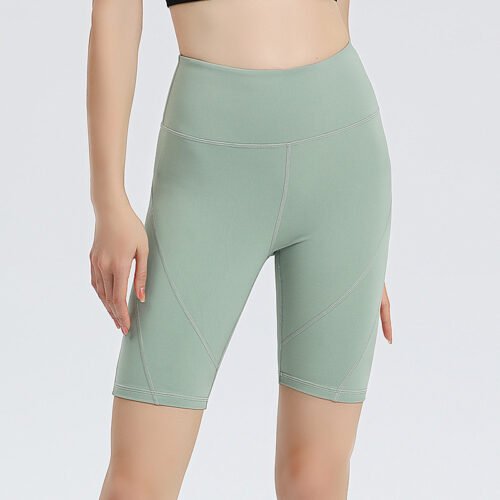 coral pink high-waisted athletic shorts. The shorts are made of stretchy, form-fitting sportswear fabric with diagonal light-toned stitching detail on the sides.