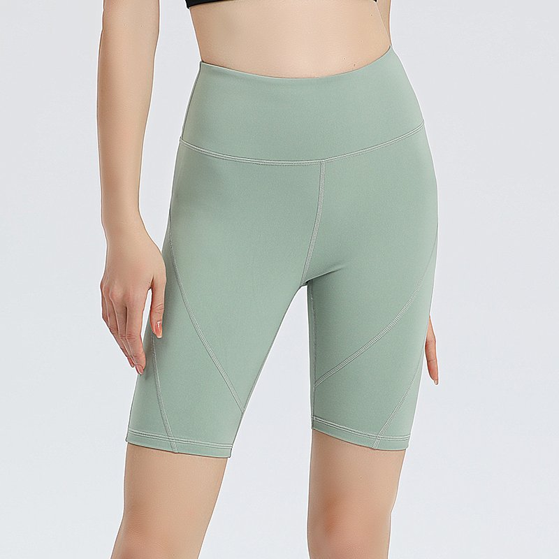 coral pink high-waisted athletic shorts. The shorts are made of stretchy, form-fitting sportswear fabric with diagonal light-toned stitching detail on the sides.