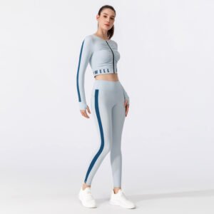 A light gray tracksuit. The set includes a short zip-up top with the blue "TWELL" letter combination printed in the center of the front, and a pair of high-waisted leggings with blue stripes on the sides.