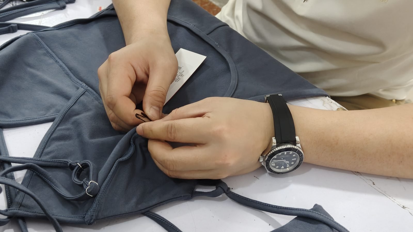 Attaching hangtags to navy bikinis by hand before packing