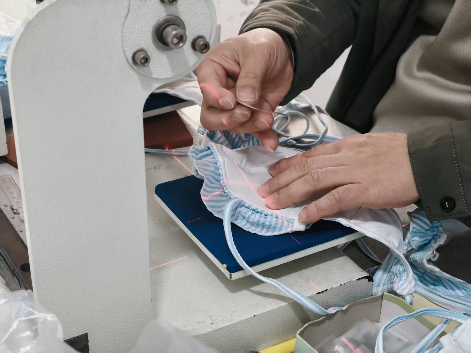 Heat-pressing a care label onto a striped swimsuit with laser-guided alignment