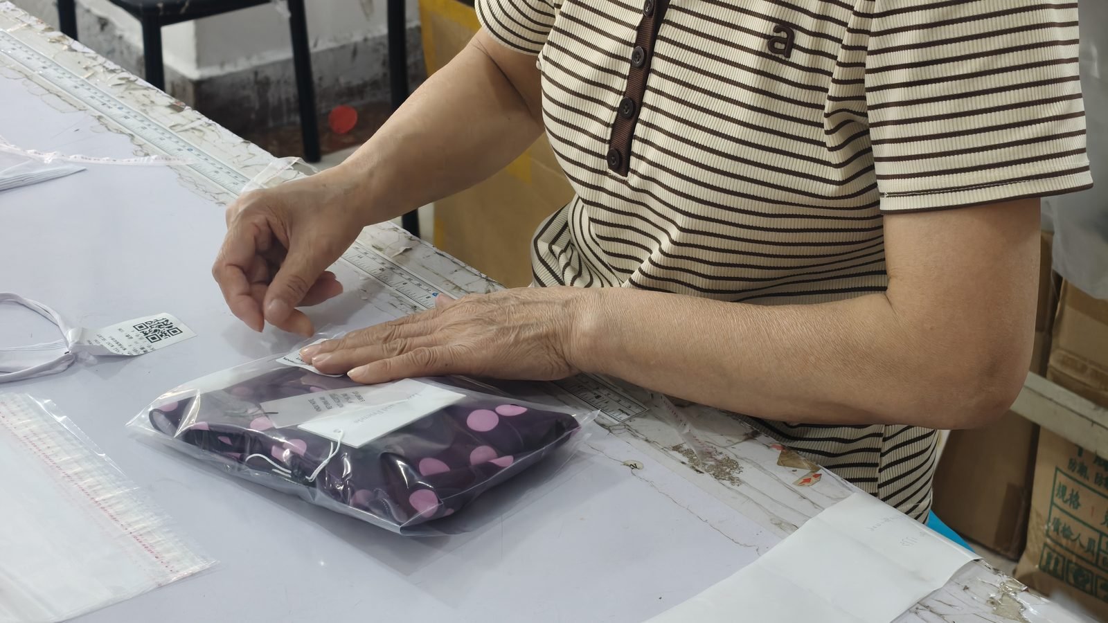 Worker folding and bagging a finished swimsuit at the packing station