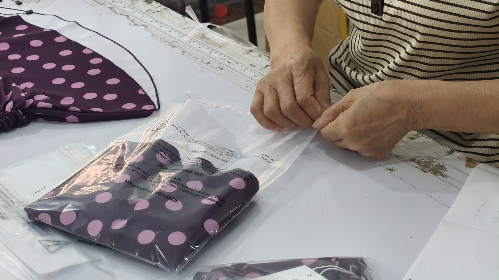 Packing swimwear into polybags printed with multilingual suffocation warnings for retail compliance
