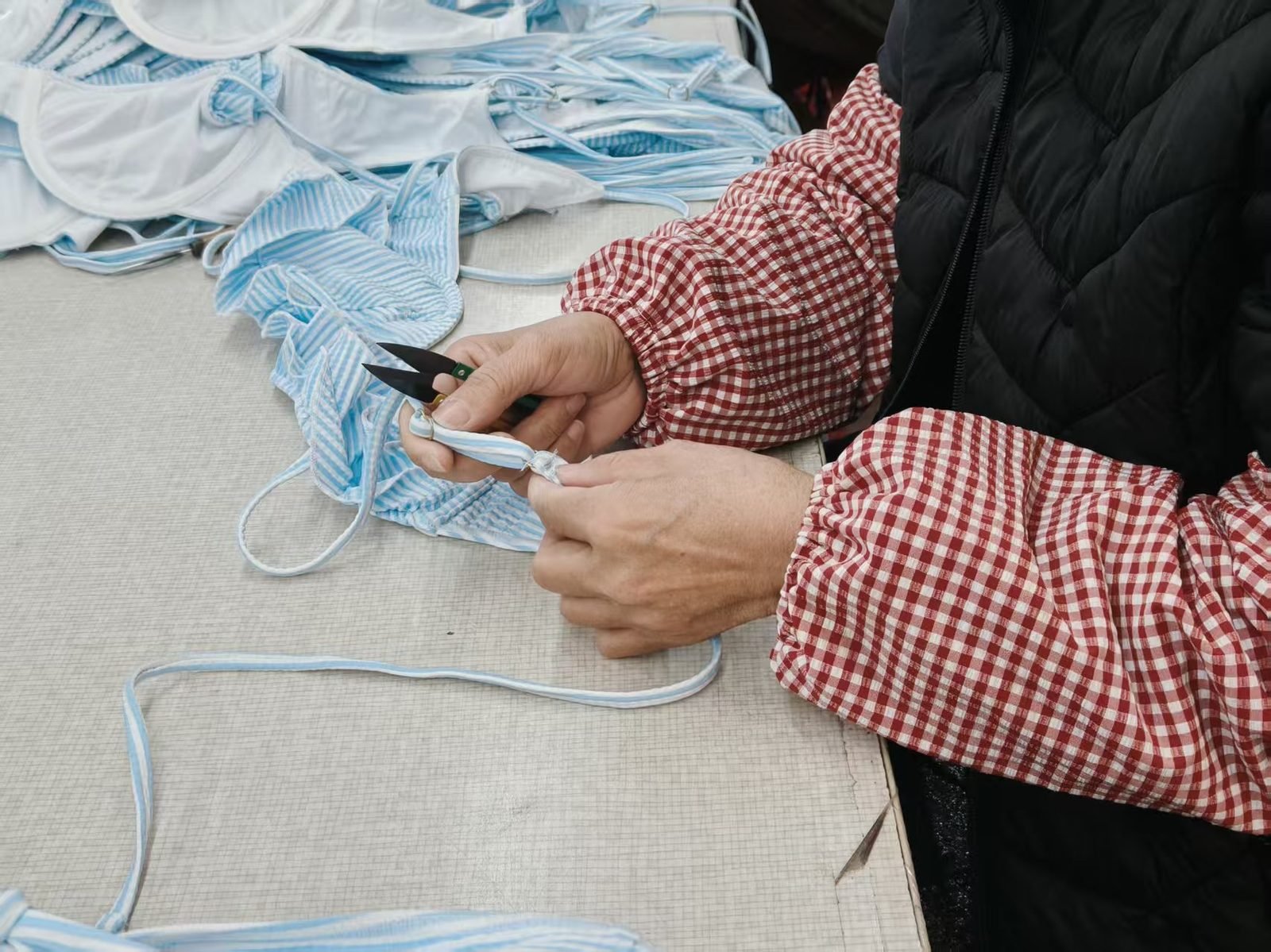 Trimming loose threads on striped bikinis during final quality control